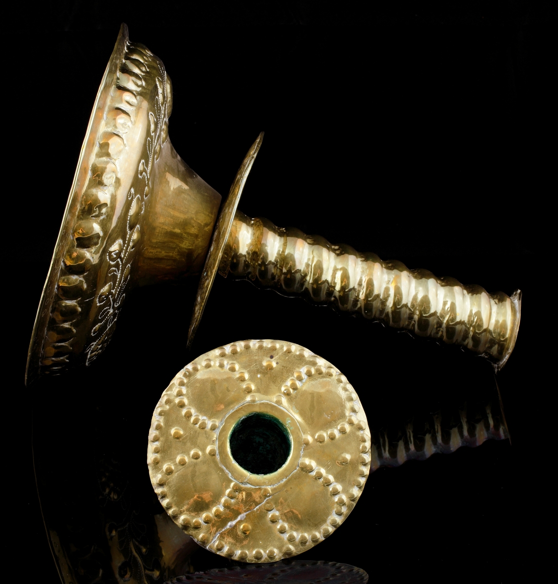 Barockljusstake av mässing, med rund fot och spiralvridet skaft. 
Foten är något kupad samt dekorerad med uthamrade växtornament.