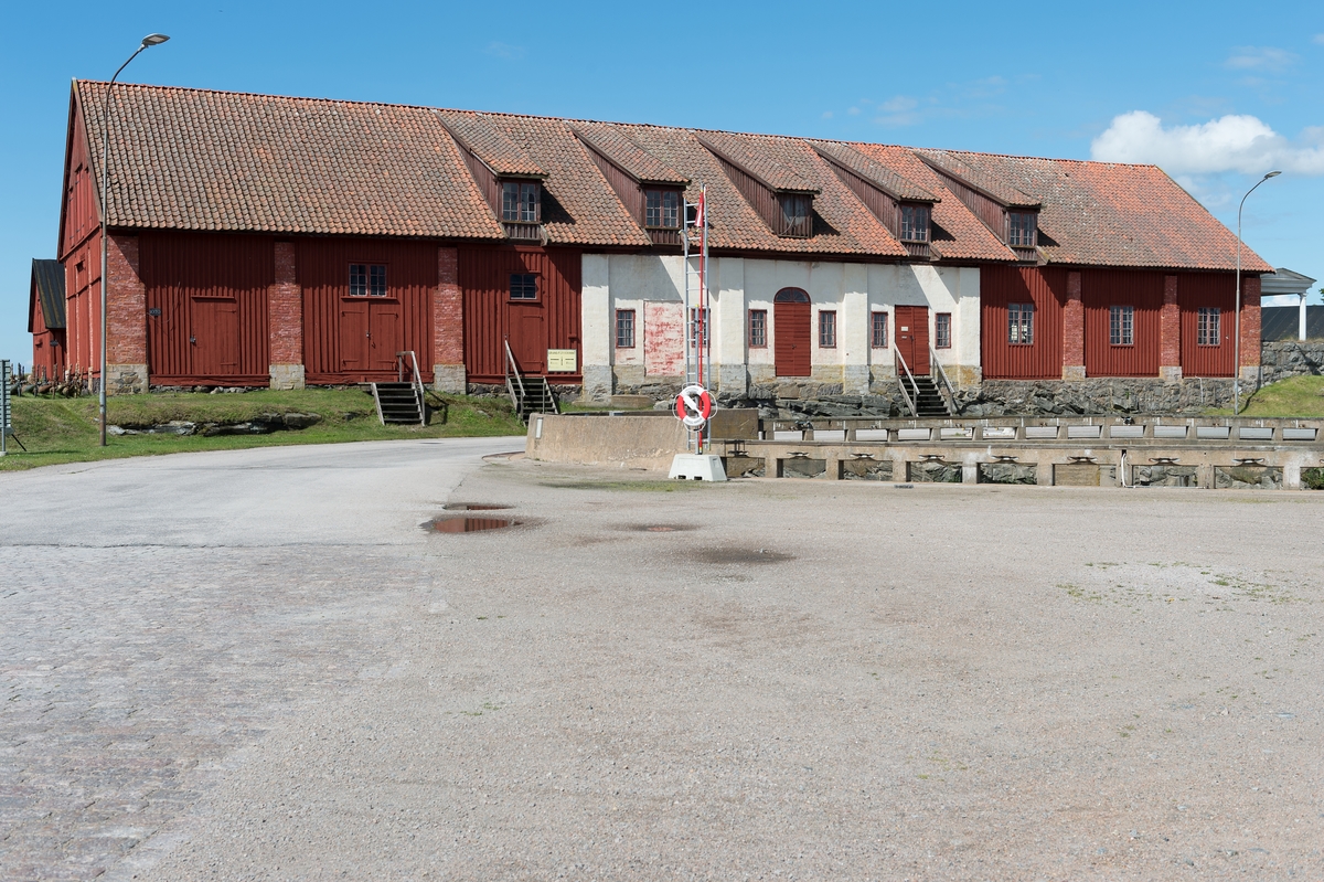 Fotodokumentation av byggnader på Lindholmen i Karlskrona. Granknäskjulet eller senare benämning knäskjulet. I denna byggnad handskades det med "knä" det var naturvuxna krokiga detaljer som användes vid skeppsbyggandet. Virkesskjul bakom granknäskjulet.
