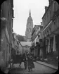 Skioptikonbild med motiv från gatan Rue Latière i Bayeux med katedralen i bakgrunden.
Bilden har förvarats i kartong märkt: Resan 1908. Bayeux 8. XI.