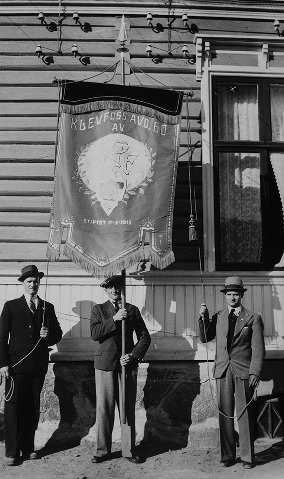Klevfoss Cellulose og Papirfabrikk, Gruppe 3 menn, FRA VENSTRE OTTO KLØVSTAD, GUTTORM AAS, OG RUDOLF LARSEN med fane. "Klevfoss avd. 60 av NPF, stiftet 11-5-1913"
Dublett: 0415-03643