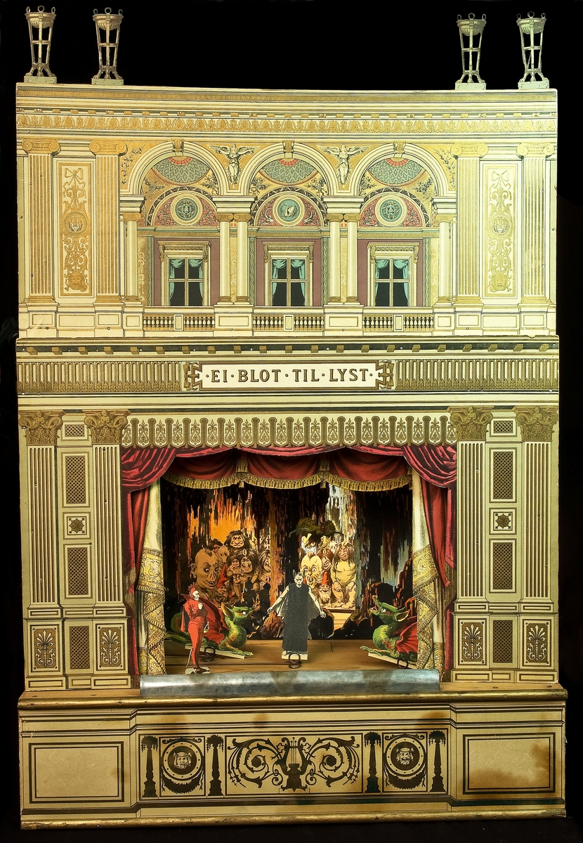 Dockteater bestående av flera tablåer och med lösa figurer (som kan dras på en skena fram och tillbaka). Teatern är delvis hopmonterad. På frontstycket på den uppmonterade teatern står: "Ei blot till lyst". Tillverkad i Danmark.
En del av teatern är nedmonterad och arkiverad med program, manus och priskurranter (ca 340 delar).