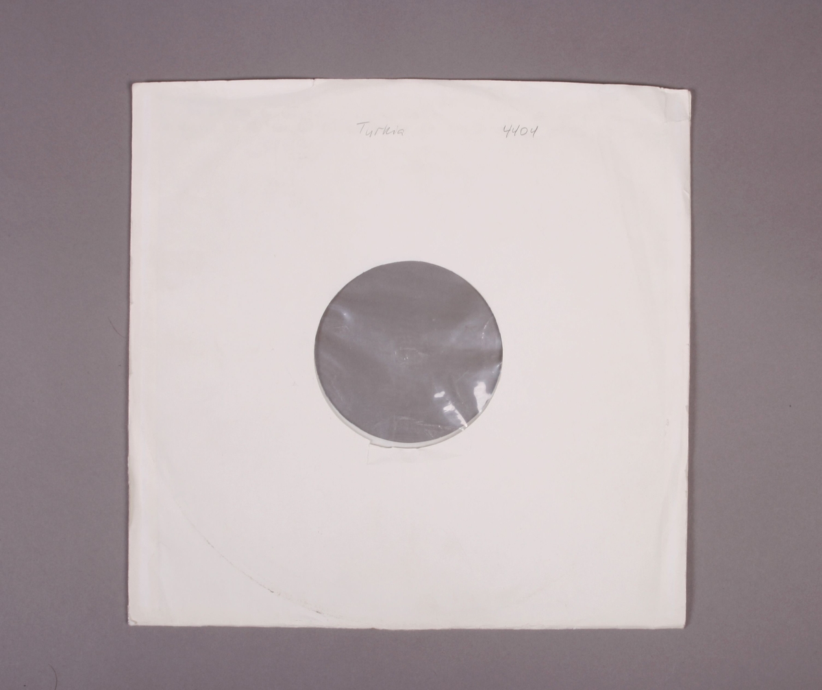 Grammofonplate i svart vinyl. Plata ligger i en papirlomme med påskriften "Trykia 4404". Ligger ved to identiske hefter, hvor på det ene har noe håndskreven påskrift (se bilde).