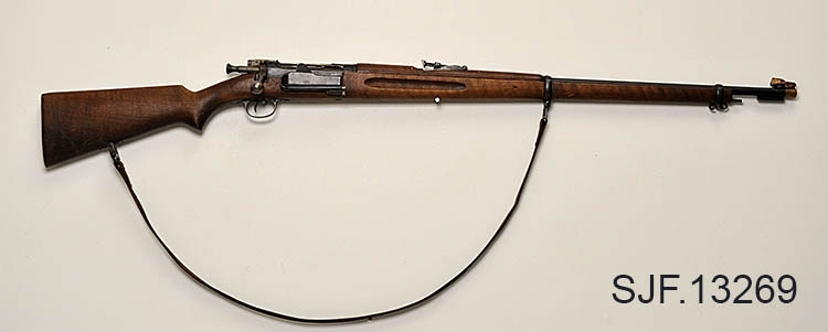 Krag-Jørgensen rifle med kaliber 6, 5 x 55. Geværet har pistolgrep. Magasinkapasitet på 5 patroner. Kolben er brunbeiset / oljet. Kolbekappe av stål. På munningen er det festet ei messinghette, en snø- og vannbeskytter. Geværet er utstyrt med høydejusterbart skur og sidejusterbart korn. 
Det er bærereim påmontert geværet. 