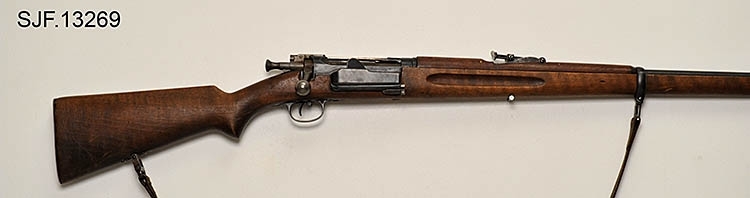Krag-Jørgensen rifle med kaliber 6, 5 x 55. Geværet har pistolgrep. Magasinkapasitet på 5 patroner. Kolben er brunbeiset / oljet. Kolbekappe av stål. På munningen er det festet ei messinghette, en snø- og vannbeskytter. Geværet er utstyrt med høydejusterbart skur og sidejusterbart korn. 
Det er bærereim påmontert geværet. 