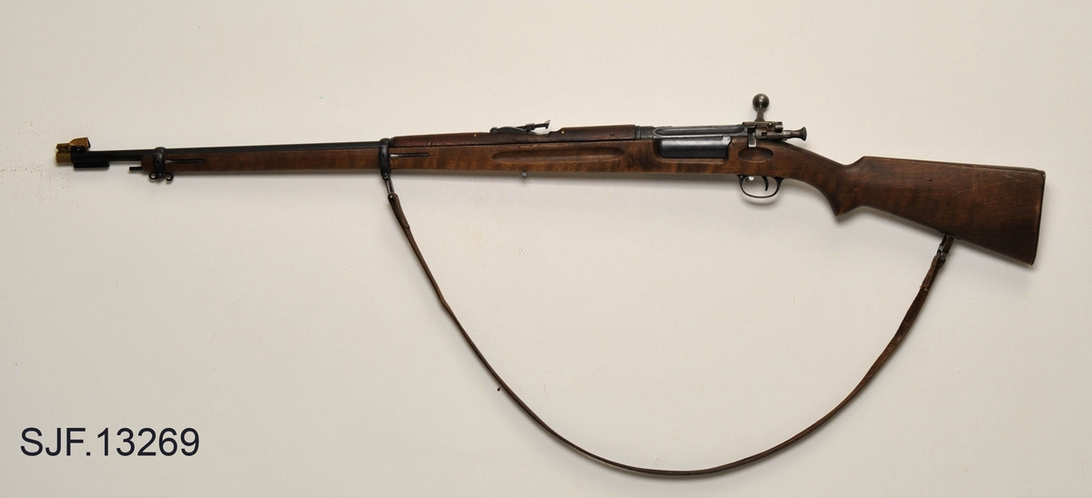 Krag-Jørgensen rifle med kaliber 6, 5 x 55. Geværet har pistolgrep. Magasinkapasitet på 5 patroner. Kolben er brunbeiset / oljet. Kolbekappe av stål. På munningen er det festet ei messinghette, en snø- og vannbeskytter. Geværet er utstyrt med høydejusterbart skur og sidejusterbart korn. 
Det er bærereim påmontert geværet. 