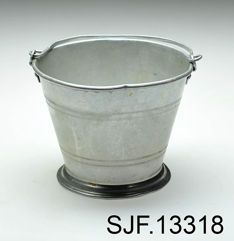 Bærspann i aluminium. Spannet har en fot som er noe breiere enn spannets bunn, og det er preget inn 4 striper langs spannets utside. Det er festet en bærehank til spannet. 

Spannet er brukt av giver da hun var ei lita jente, og av hennes mor som var født ca. 1910. Spannet ble brukt på bærtur. Giver forteller at det til sammen har blitt båret mange hundre kilo blåbær i dette lille spannet. Plukkested var først i Heradsbygda, og deretter Jømna. 