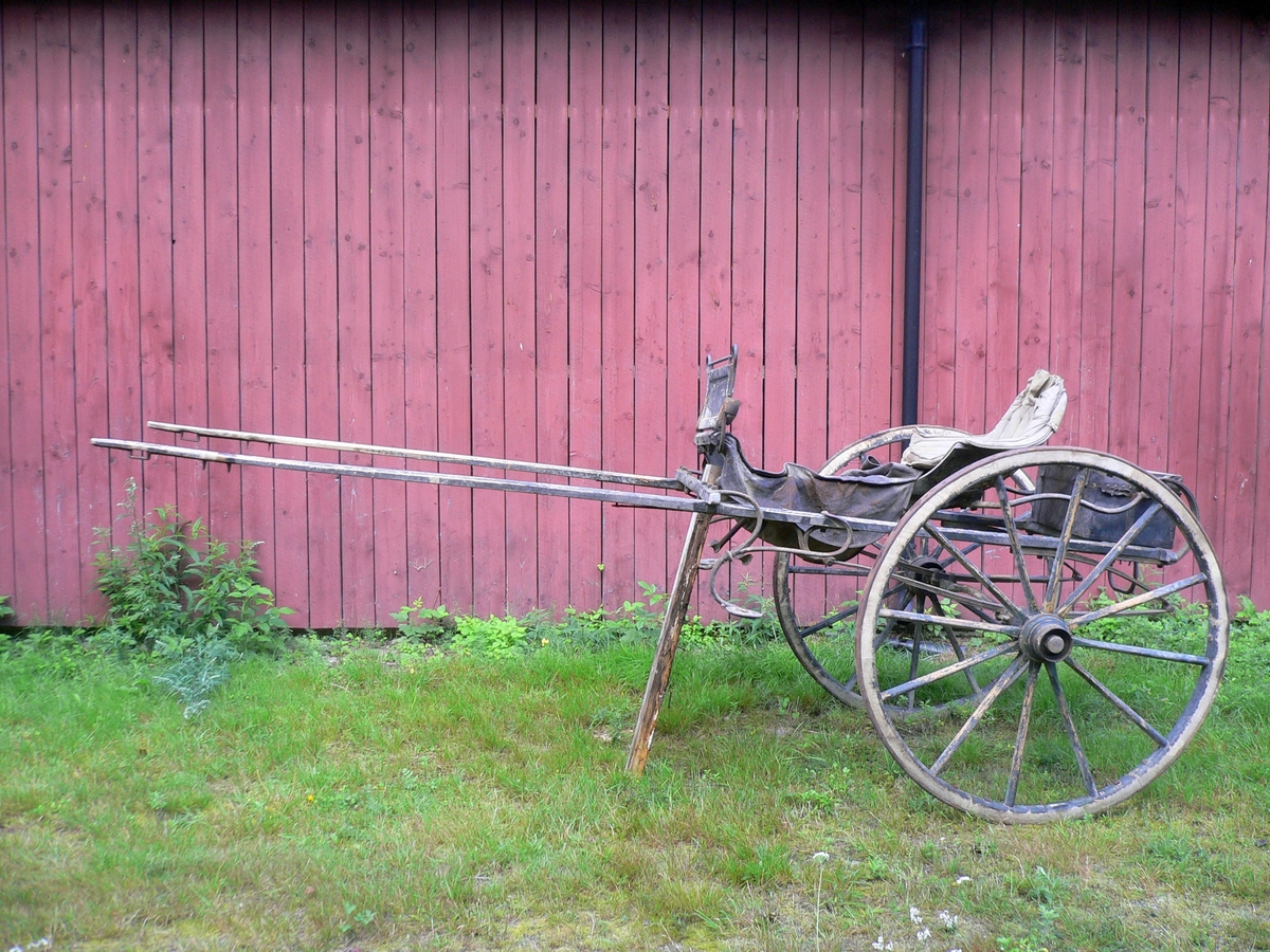 2-hjuls vogn for én hest til persontransport. Hovedsete for én person. Skrin med polstret lokk for skyssgutt.