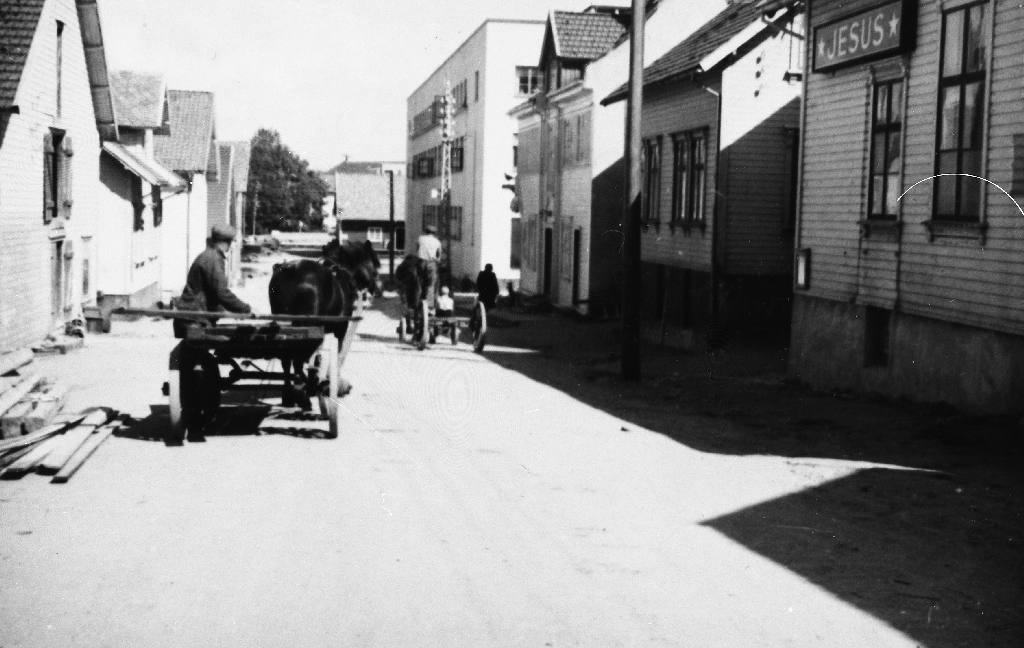 Meierigata sett mot jernbanen i 1950 åra. Frelsesarmeen, Fjogstadhuset, Apoteket "Viben" og meieriet på høgre sida. T.v. : J. Kindervaag, Saron og J.C. Laland. I bakgrunnen "Godsen" - jernbanen.
Same bilete som 1989.1TIM. 3. 42