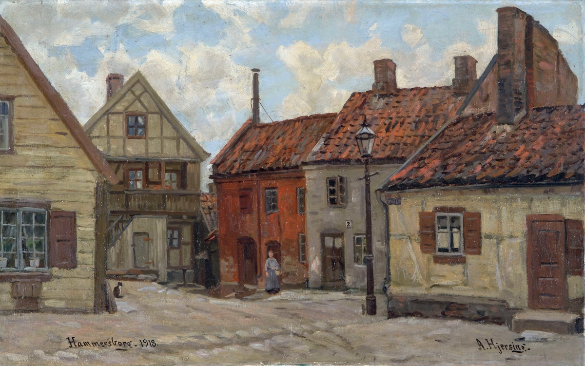 Sett fra Bjerget. I bakgrunnen ligger Kanten 3b. Til h. ligger et gult, et grått og et rødt hus. Det grå huset er Kanten 2. Foran det røde huset står en blåkledd kone. 