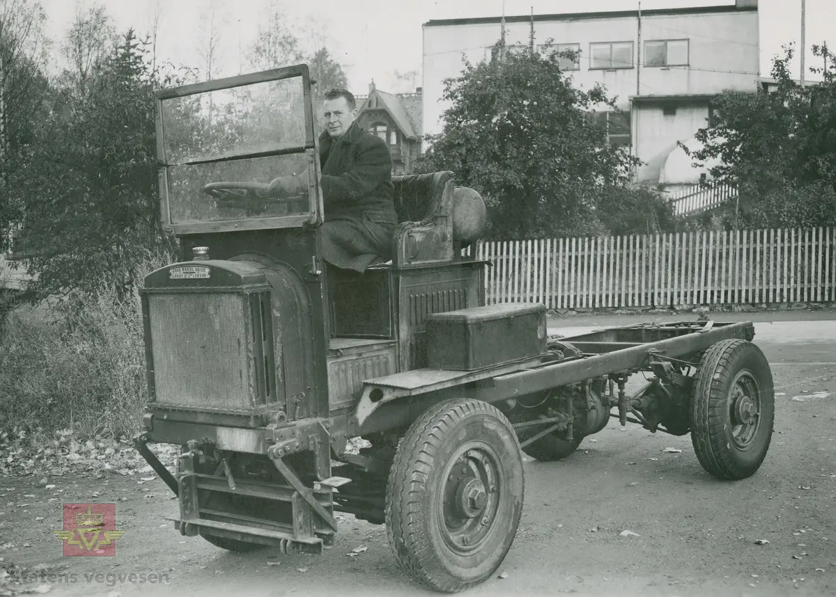 "FWD lastebil modell 1918. Brukt som brøytebil av Lillehammer by fra 1925-1945. Motorstørrelse 36 HK.  Denne type fra engelsk overskuddslager etter første verdenskrig ble brukt til brøytebiler som brannbiler i stort antall. Merk NB: eneste lastebil med firehjulsdrift." I følge merking i album. Klikk på pilen til høyre: Bilde 1 og 2 viser FWD lastebilen og med Johnny Colbjørnsen sittende i førersetet. 

3):  Samme vogn levert Aker kommune utenfor Oslo. Ved rattet Colbjørnsen & Co A/S testsjåfør Edlund. Medhjelper: Firmaets senere juniorsjef." I følge merking i album.  "Nils All Colbjørnsen ca. tre år ved rattet i en av de første FWD-vognene som ble tatt inn fra militært overskuddslager i England. Mannen i skinnlue er demonstrasjonssjåfør Stener Edlund. Johnny Colbjørnsen var flink til å skape blest om sine produkter, og vognene han solgte til Akers veivesen var rene reklameplakatene. Det ga også god omtale å brøyte banen for racene på Gjersjøen tidlig i tjue-årene. I referatene fra løpene var det ikke bare bilder av racerbilene, men også av brøytebilen til Colbjørnsen. "Sitat fra boka: "Familiefirmaet-utenom allfarvei/2000 årsboken." Colbjørnsen & Co A/S, av Bjørn Ausjen Johannessen. 

"FWD er det bilmerket som har betydd mest for utviklingen av en effektiv brøytetjeneste på norske veier. Det ble til og med holdt kinoforestillinger rundt omkring i landet for for at folk kunne få se disse bilene med firehjulsdrift  i aksjon."
"Første generasjon FWD var ikke akkurat noen skjønnhet, men overbeviste med sin frammkommelighet. "Forhjulene trækker - bakhjulene skyver paa, det er hva der menes med Four Wheel Drive" forklarte Colbjørnsen i den første salgsbrosjyren fra 1919.  "Klumpen" under bilen er "centraldifferentialet" (fordelerkassen), som kunne sperres med de to spakene på fordelerkassen som er synlig på bildet. Sjåføren eller hjelpemannen måtte altså gå ut av bilen for å bruke spakene. Overføringen fra girkassen til fordelerkassen foregikk via kjede." Sitat fra:  "Norsk lastebilleksikon. De første 40 årene. Lastebiler i Norge 1900-1940," side 94, av Asbjørn Rolseth.