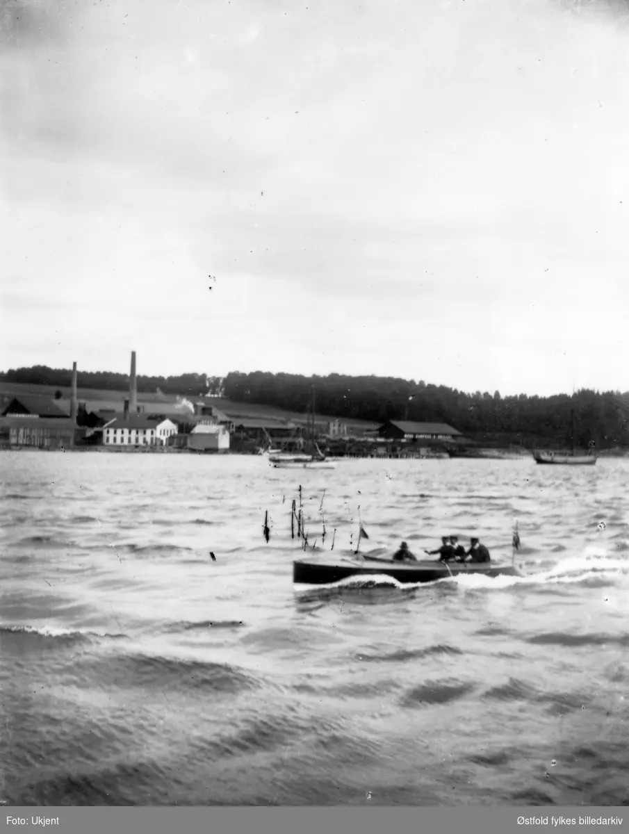 Bilde tatt fra Værla mot fastlandet - ant. fabrikk eller teglverk i bakgrunnen, ca. 1920-30. I forgrunnen en hurtiggående motorbåt.