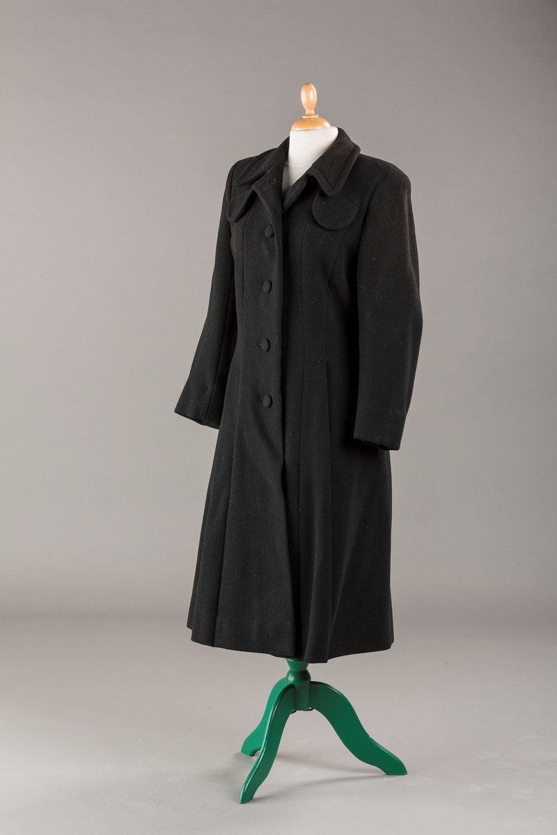 Innsvinget liv, pynteklaffer ved brystet foran. 
Stikklommer foran.
Skulderputer
Fire trukne knapper
Avrundet krage