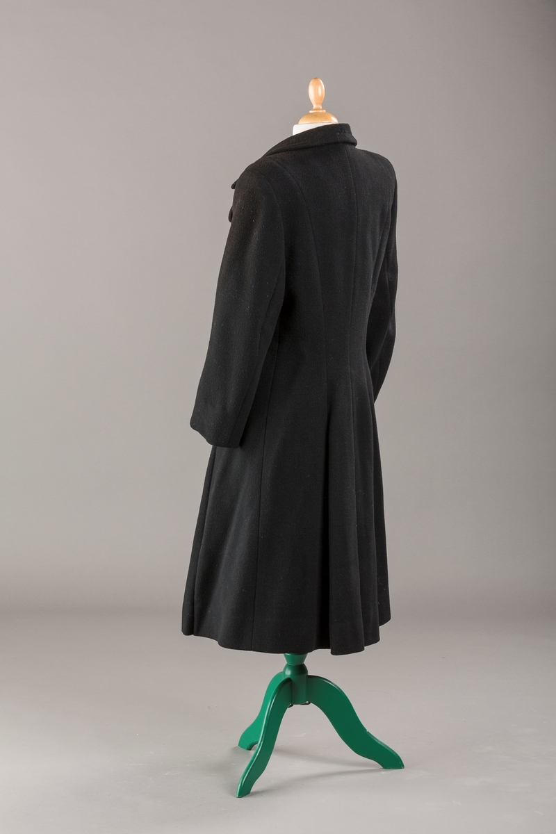 Innsvinget liv, pynteklaffer ved brystet foran. 
Stikklommer foran.
Skulderputer
Fire trukne knapper
Avrundet krage