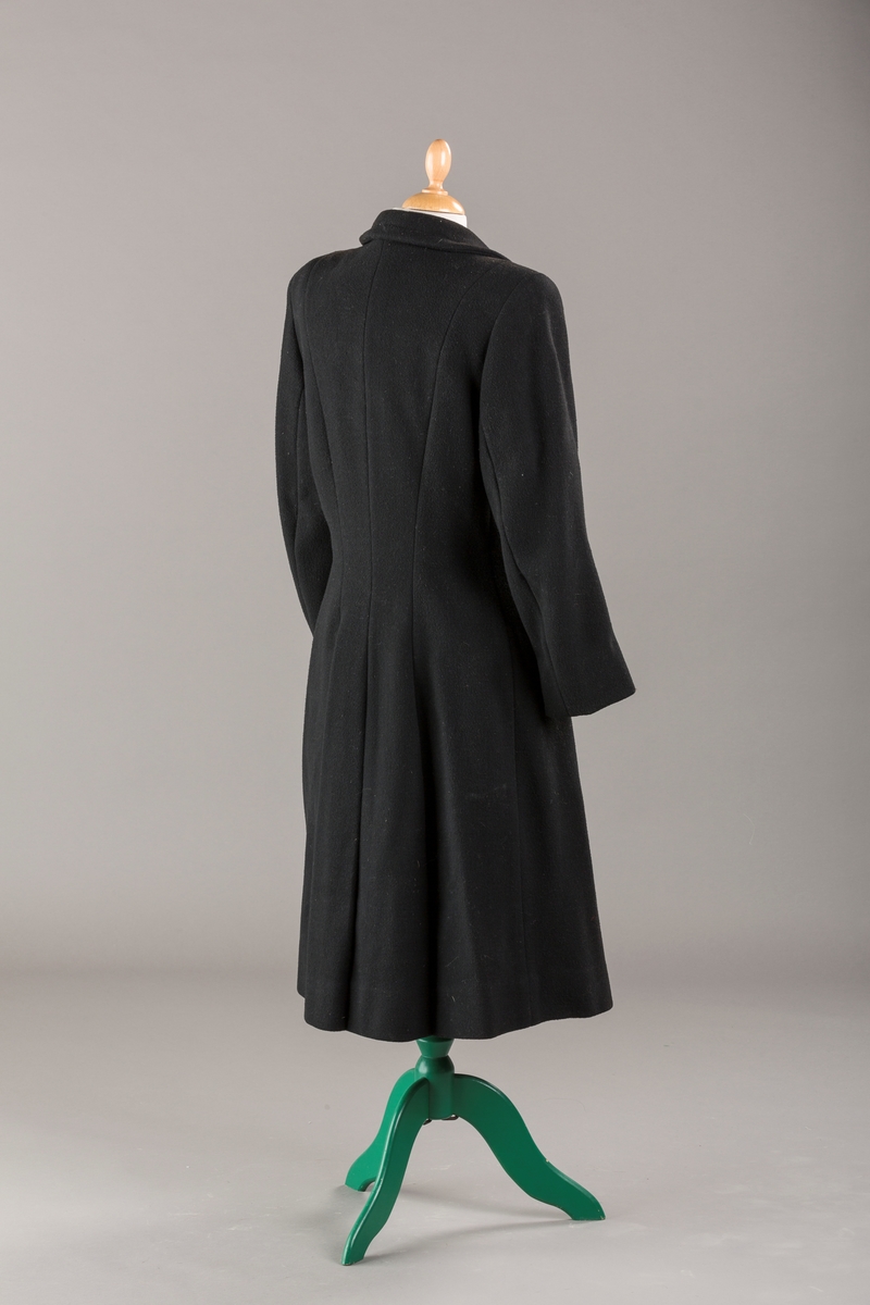 Innsvinget liv, pynteklaffer ved brystet foran. 
Stikklommer foran.
Skulderputer
Fire trukne knapper
Avrundet krage