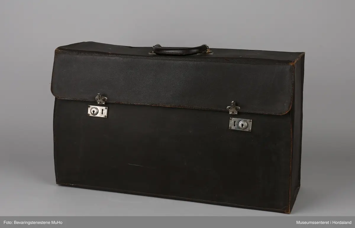 Rektangulær koffert i brunt skinn med eitt rom. Brukt av seljar ved Irisfabrikken i Os. Brukt til å oppbevare og transportere prøvar på kolleksjonen til potensielle kundar.
