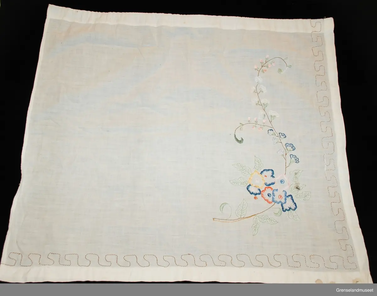 gardinene består av to små fag for nederdelen av stuevindu. Brodert med blomstermotiv i tungesting, kontursting og sjattersøm. Rundt gardinen er en z-kant sydd med sparesting. Løpegang for gardinwire.