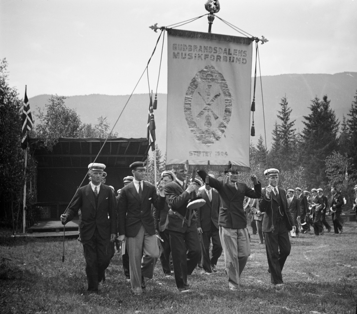 Opptog med musikkforening og fanen til Gudbrandsdalens Musikkforbund ved pyntet utescene.
