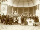 Tysk historisk tablå, grupp i uniformer uppställd vid musikpaviljong, 1900-talet.