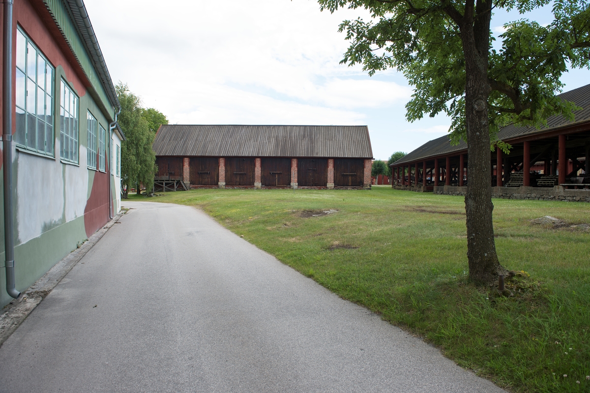 Fotodokumentation av byggnader på Lindholmen i Karlskrona.                 T. v. MTB-hallen. Mitten:  Skjul för förvaring av ekvirke. Skjul 13, 14, 15, ritades av överstelöjtnant-mekanikus Jonas Lindströmer. Byggnaderna uppfördes omkring sekelskiftet 1800. Slitaget t h. byggdes omkring 1850 och användes som virkesskjul. De runda träpelare ska ha varit utrangerade mastträn. Byggnaden är ca: 96 meter.