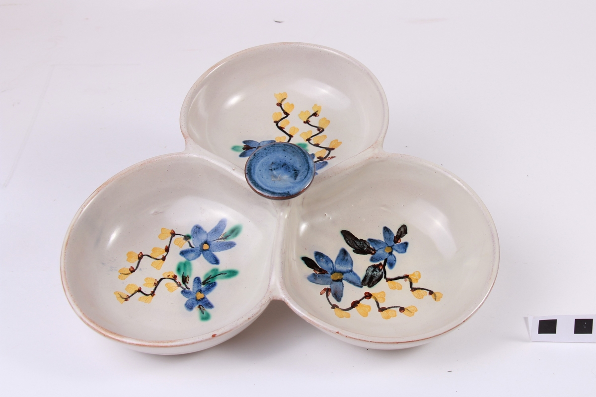 Kabaretfat i gråkvit farge med blomster i blått, gult, grønt og svart.