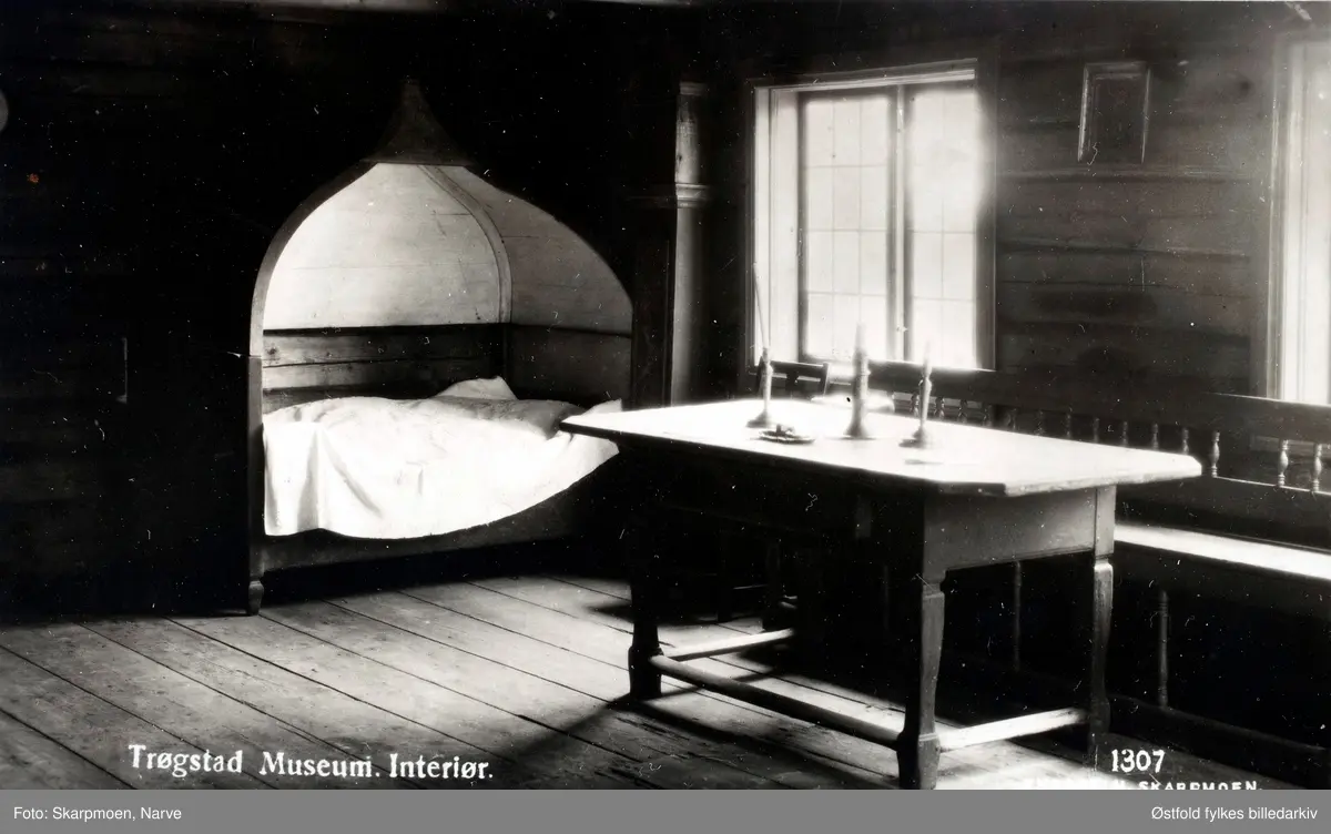Trøgstad Bygdemuseum. Raknerudbygningen. Interiør. Postkort. 
Raknerudbygningen er en stuebygning med svalgang fra 1777.
Trøgstad Bygdemuseum er et av de første bygdemuseer i landet. Museet ble innviet på Olsokdagen 29. juli 1928,