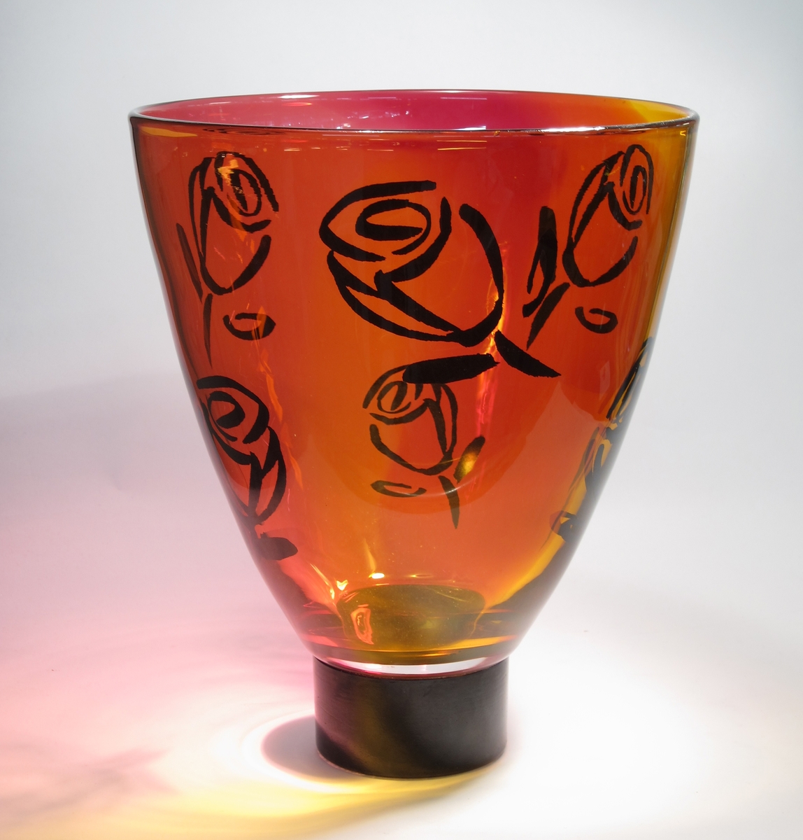 Vas "Rose".
Stor och hög vas i rödrosa och gult, med svarta rosor.
Vasen är blåst i tappfärger (olika färger har satts samman) och driven. Blommorna är dekaler.