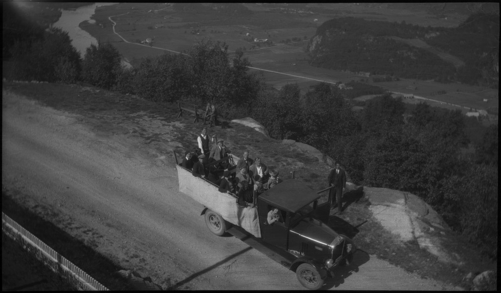 Biltur til Kvinesdal. Det er bilder tatt fra bilen fremover på veien og utover landskapet. Det er også bilder fra et tettsted ved en fjord. På bilde nr. 8 står det et hus med påskriften "HANSEN" på den andre siden av ei bru. På bilde nr. 17 sitter antageligvis Harald Bergsaker og Arne Johannessen på en stein i ei stri elv. Det er også flere bilder av en gruppe mennesker med en åpen buss. På bilde nr. 14 er L. A. B. Ådnesen til venstre.