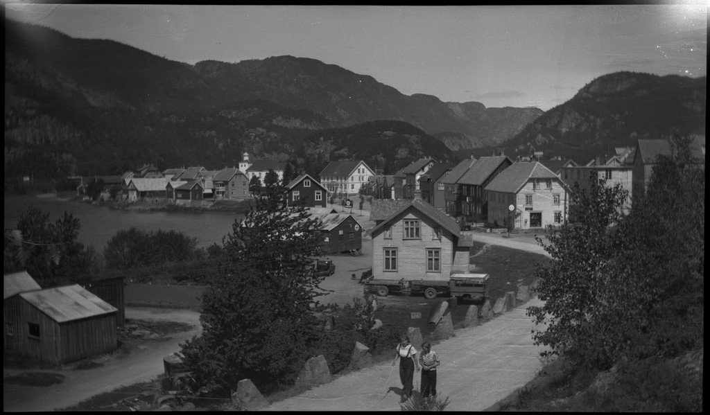Biltur til Kvinesdal. Det er bilder tatt fra bilen fremover på veien og utover landskapet. Det er også bilder fra et tettsted ved en fjord. På bilde nr. 8 står det et hus med påskriften "HANSEN" på den andre siden av ei bru. På bilde nr. 17 sitter antageligvis Harald Bergsaker og Arne Johannessen på en stein i ei stri elv. Det er også flere bilder av en gruppe mennesker med en åpen buss. På bilde nr. 14 er L. A. B. Ådnesen til venstre.