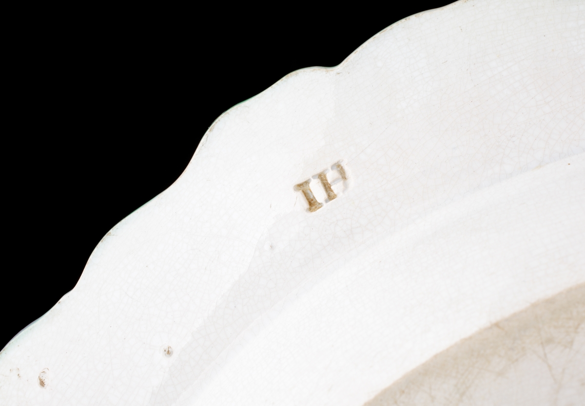 Stekfat av flintgods.
Oval modell. Vitglaserat med grön s.k. "feather edge"-kant. På fatets spegel monogram i vinrött: "JS". 
På fatet fäst en lapp med text: "Johan Sergel (1740-1814), adlad professor vid Konstakademin, Johan Sergel 1800-10, Inköp".