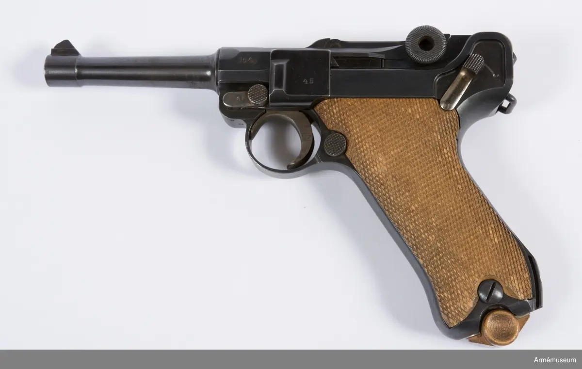 Kolvsidor av trä.
Hölster och extramagasin saknas.
Stämpel på ovansida från Deutsche Waffen- und Munitionsfabriken (DWM), Berlin. Där tillverkades de allra flesta av Parabellumpistolerna mellan 1900-1930.