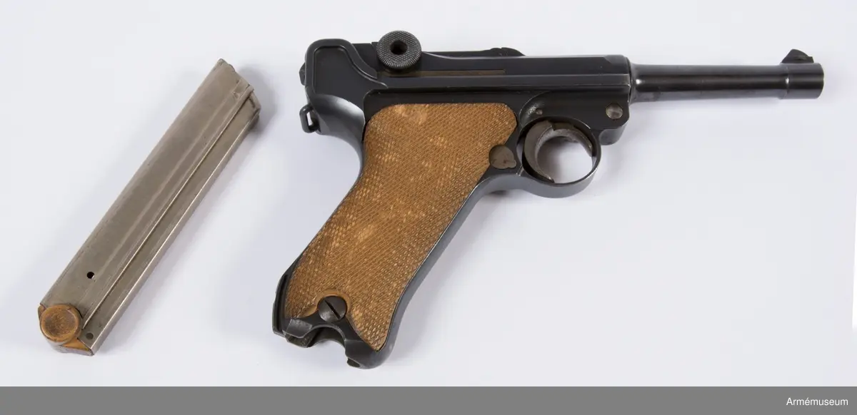 Kolvsidor av trä.
Hölster och extramagasin saknas.
Stämpel på ovansida från Deutsche Waffen- und Munitionsfabriken (DWM), Berlin. Där tillverkades de allra flesta av Parabellumpistolerna mellan 1900-1930.