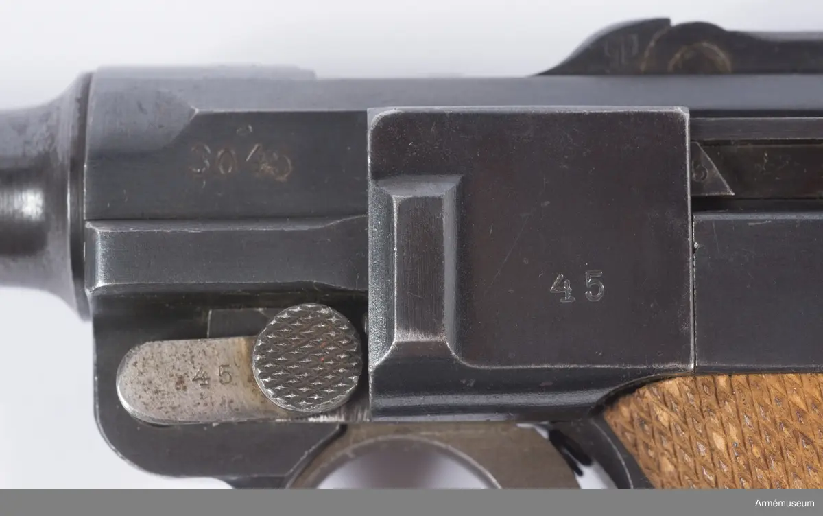 Kolvsidor av trä.
Hölster och extramagasin saknas.
Stämpel på ovansida från Deutsche Waffen- und Munitionsfabriken (DWM), Berlin. Där tillverkades de allra flesta av Parabellumpistolerna mellan 1900-1930.