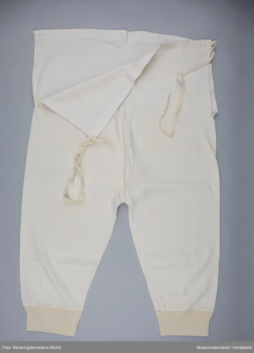 Lang Pedek bomullsunderbukse med snøringar i sidene og knappar. Lerretsstoff i linninga i livet, str. 50. I plastemballasje.