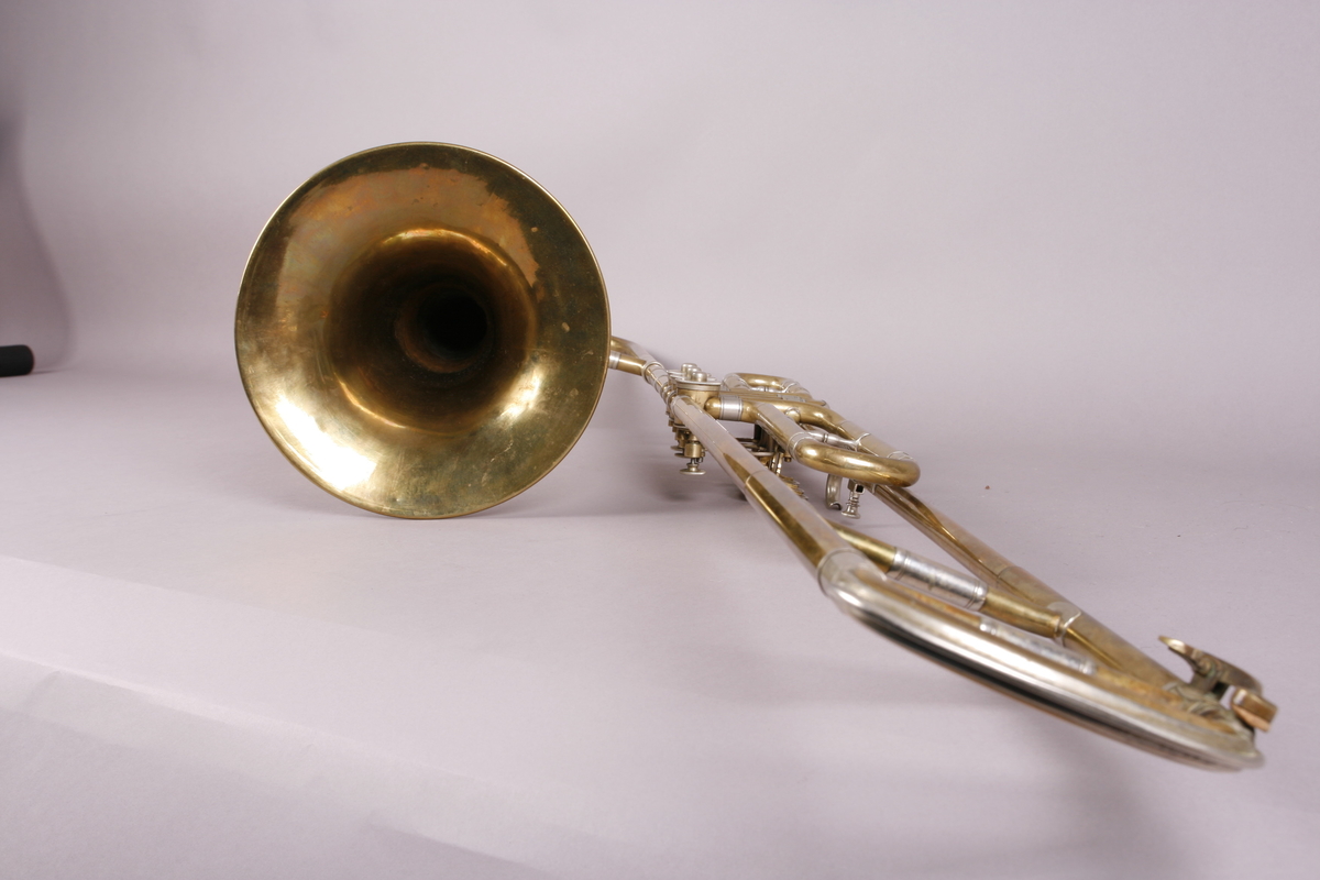 Ventilbasun, eller trombone, i messing, med dreieventiler. Tilhørende munnstykke.