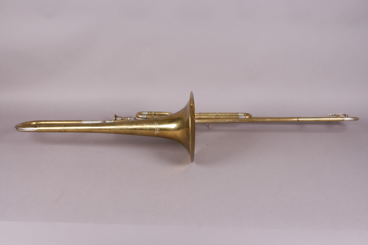 Ventilbasun, eller trombone, i messing, med dreieventiler. Tilhørende munnstykke.