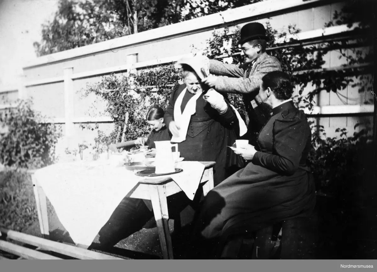 Damer med hatter har teselskap i hagen. kaffe, saft. ca 1900. Oslo?  Samlingen har tillhørt Gert Faye-Gunnerud hvis mor var fra Walther-slekten i Kristiansund. Giver av samlingen er Tore Kristiansen. Fra Nordmøre museums fotosamlinger.