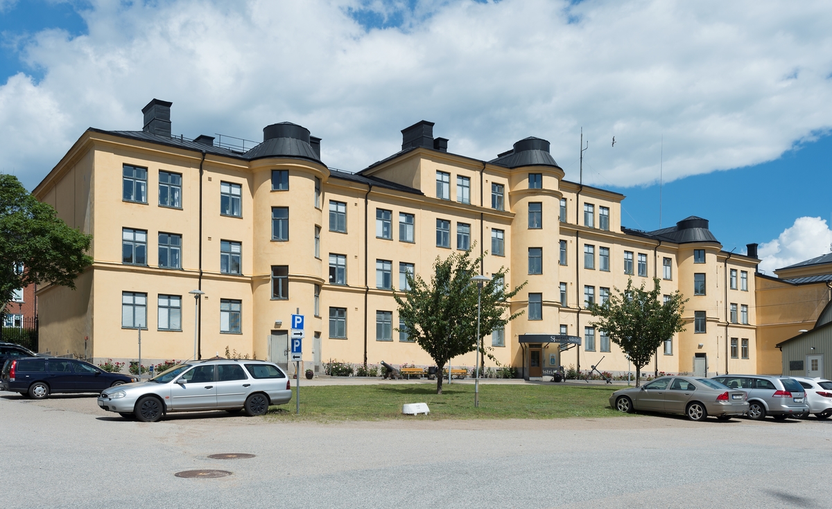 Byggnad i tre våningar. Slätputsad gul fasad med tre inhysta trapphus.
