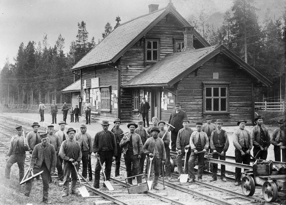 Jernbanearbeidere foran stasjonsbygning