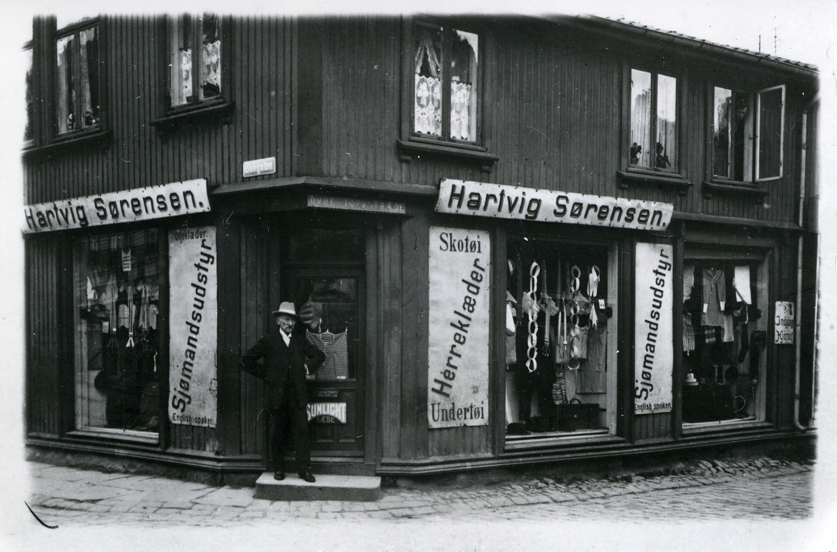 Fredrikstad, Vestsiden. Bakgaten (Fra 1955: Farmannsgaten). Bakgaten 3. Hjørnet Bakgaten/Øvre Torvstræde, Hartvig Sørensen, konfeksjonsforretning for arbeidsklær og sjømannsutstyr, Hartvig Sørensen (stående utenfor).
