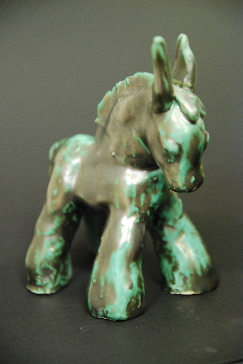 Figurin, mulåsna, lergods, grönsvart glasyr, formgiven av Märta Willborg, 1930-talet.
