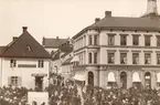 Motiv mot del av Stora torget i Linköping. Vy mot väster. Enligt påskrift togs bilden i juni månad 1884. Närmast till vänster ses del av makarna Qvilléns gård. Handlare Lars Eriksson öppnade sin butik i hörnhuset 1880. Till höger Hushållningssällskapets fastighet. Byggnaden uppfördes efter att en tidigare fastighet raserats i en eldsvåda 1864. Länge drevs Sahlström bokhandel i gatuplanet, etablerad av Peter Mathias Sahlström. I bildens övre högra hörn skymtar domkyrkans nya torn som vid tiden höll på att färdigställas.