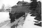 F6 Karlsborg 1940. F6-personal framför den gamla lektions- och matsalsbyggnaden och den rivna arrestbyggnaden till vänster, för krigsmans erinran den 1 april.  Även luftvärnets musikkår medverkade. Albumet är en del av en donation från Karl-Axel Hansson. Förteckning över hela donationen finns i albumet samt som Word-dokument.