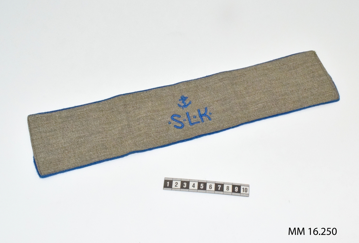 Armbindel för marinlotta. Rektangulärt tygstycke, dubbelt. Framstycket gråbrungrönt melerat, bakstycket mellanblått. Bakstycket bildar blå passpoal runt det gråbrungröna stycket. På framstyckets mitt blå broderade bokstäver: S . L . K . Riksförbundet Sveriges lottakår.

Ovan emblemet blått broderat ankare: flottans emblem.