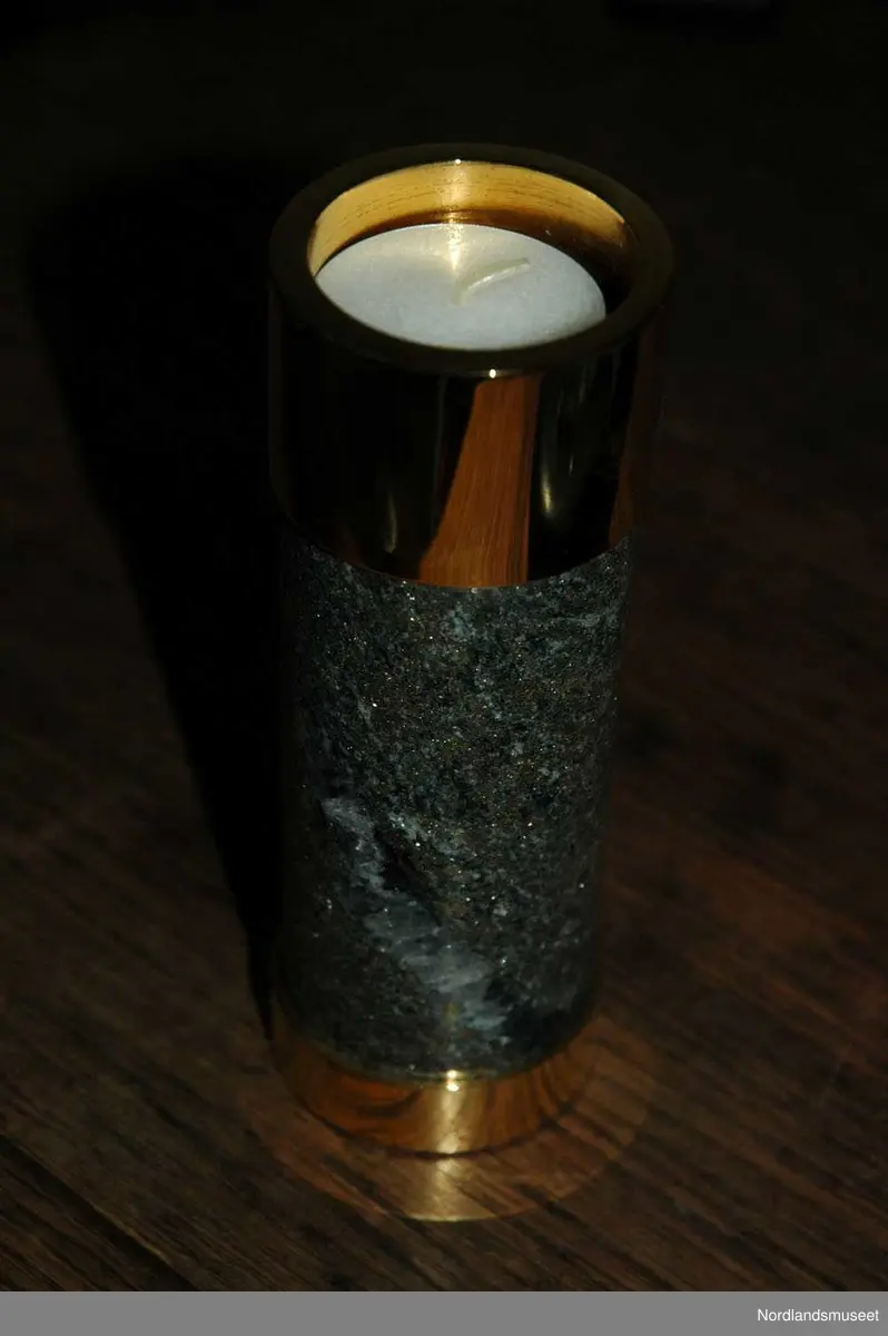 3 lysestaker med en brikke.
a: Lite lys som er laget av slipet malm og messing.
b: Mellomstort lys som er laget av slipet malm og messing.
c: Stort lys som er laget av slipet malm og messing.
d: Brikke som lysestakene står på.