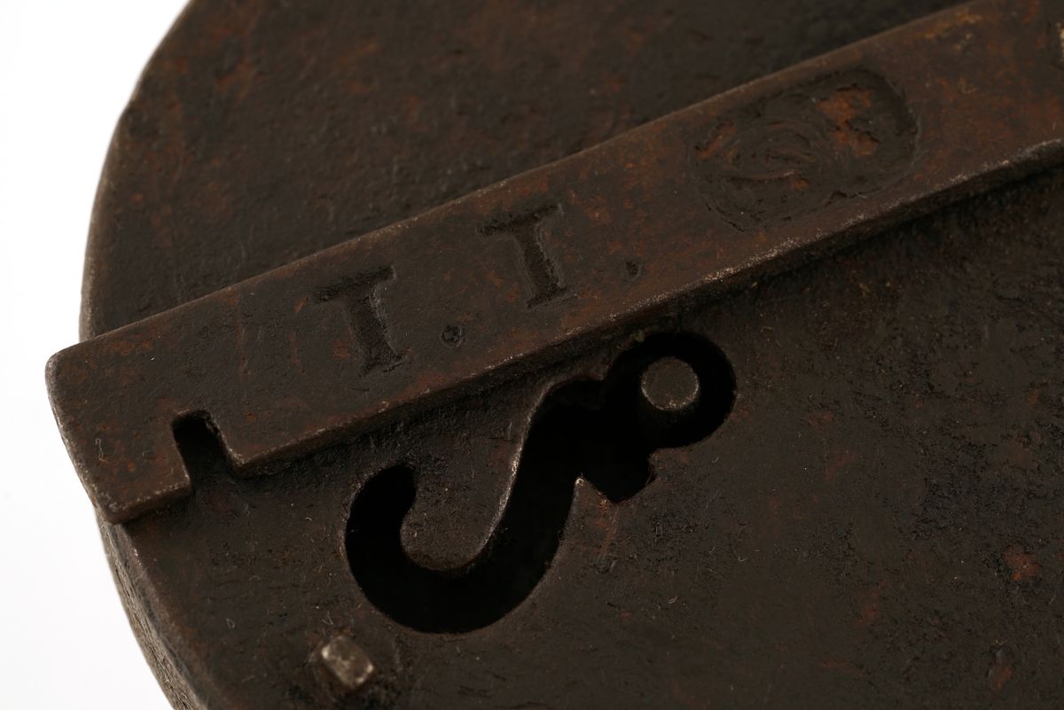 Hengelås av jern, oval med svingbart lokk over nøkkelhull.
Nøkkel av jern med skjegg formet somkroker. Gjennombrudt.