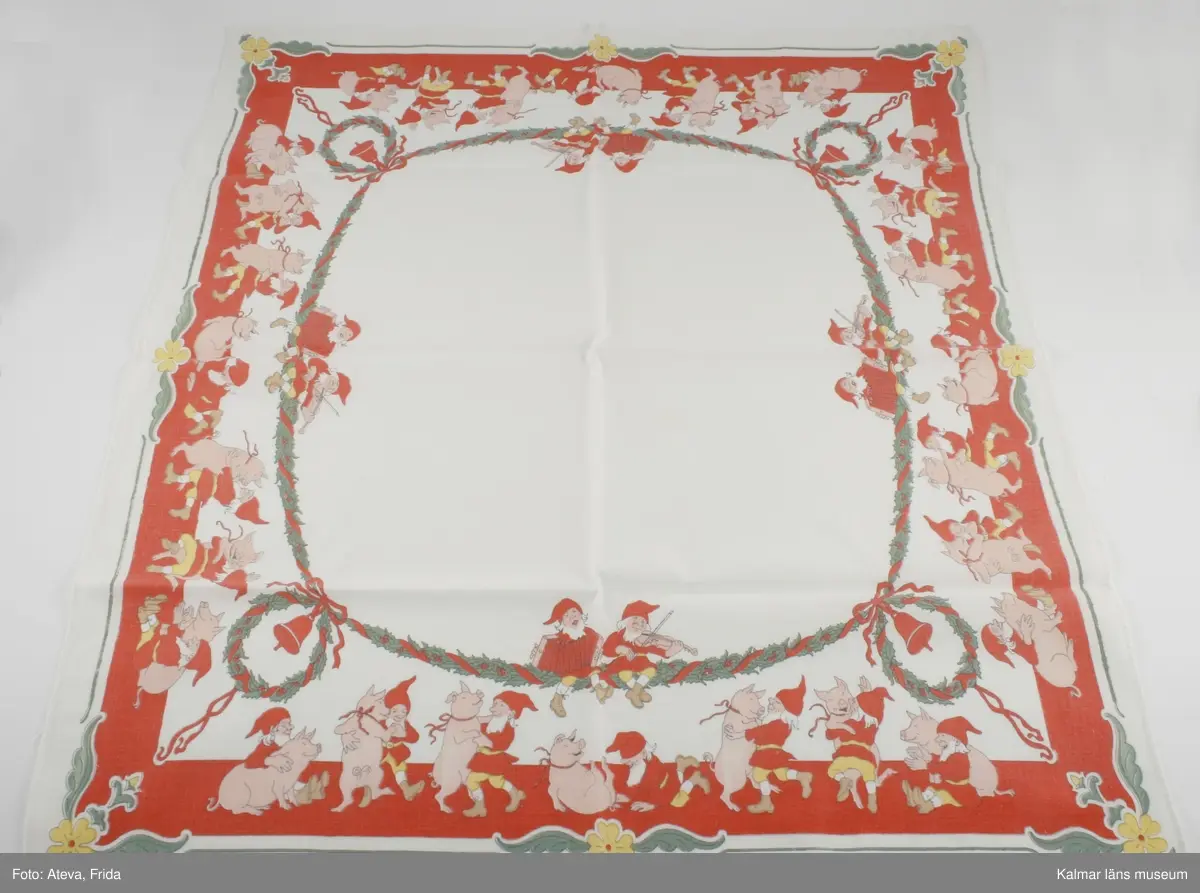 KLM 44737. Duk. Julduk. Av tuskaftad vit bomull med tryckt mönster i rött, grönt, rosa och gult. Motivet är tryckt längs ytterkanterna på duken. Ytterst bladslinga i grönt med gula blommor i hörnen och mitt på sidan. Innanför dansar tomtar och grisar i par på rött golv. Innerst järnekskrans med julklockor i hörnen. På kransens fyra lånsidor sitter ett par tomtar som spelar dragspel och fiol. I ena hörnet signaturen JN. Duken är maskinfållad i två sidor och har stadkant i två. 
Duken är tryckt efter förlaga av Jenny Nyström. Original, ej senare kopia.