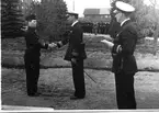 F6 Karlsborg 1940. Den 25 maj meddelades krigsmanserinran till nyinrykta värnpliktiga på F6, i samband med en fältgudstjänst. Samtidigt utdelades för första gången flygarmärke i silver m/36 som här överlämnas av chefen F6, överstelöjtnant John Stenbeck till vpl. Korpralen 796 Alm. Albumet är en del av en donation från Karl-Axel Hansson, Karlsborg. Förteckning över hela donationen finns i albumet, samt som Word-dokument.