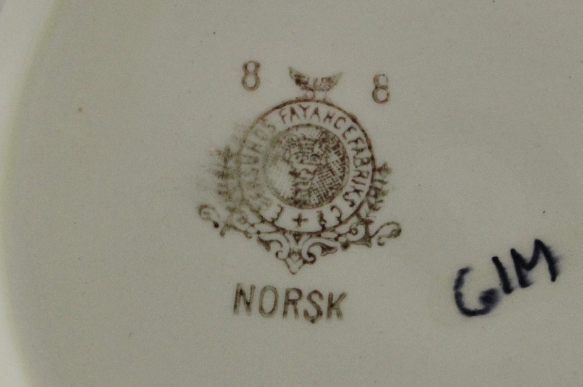 Et lokkefat, med skål og lokk, samt et ekstra lokk. Alle i samme servise fra Egersund. Skål i hvit bunn, med dekor på begge sider, blomster i rosa, blått, gult og hvitt, i tegnet korsstingsmønster. To håndtak. To lokk i hvitt med håndtak toppen, rundt håndtaket en bord med samme dekor som på skålen. Smal grønn strek både på ytterste del av lokket og øverst på skålen. Stemplet i brunt under. 8tall i stempelet skal indikere størrelse.