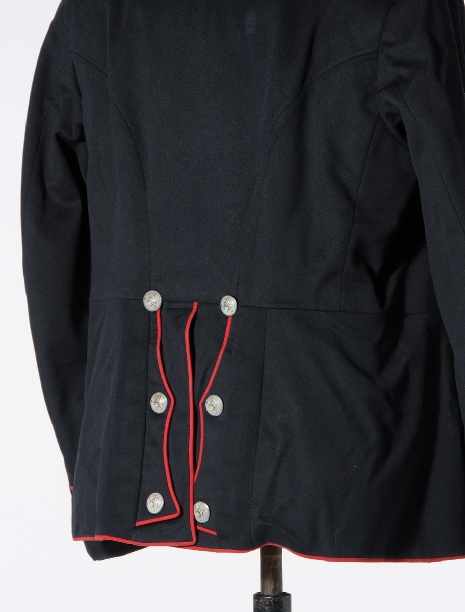 Enkeltspent jakke til uniform i mørk blå ull, med rød kanting og sølvnapper. Åtte knapper i fronten. Kraven er opprettstående og med to sølvstjerner på hver side. Skuldrene har tre påsydde hemper og metallkjede. Knappene er dekorert med norsk løve. Baksiden har splitt og tre par knapper. Rød kantdekor. Nederst på ermene er det tre smale bånd med knapp og røde kantbånd. Innvendig er jakken helforet med rødt stoff og lyst stripet stoff i ermene. Opphengshemper i ermene. Fronten er vattert. Innvendig hempe i midjen. To hekter i halsen for lukning av krave. Lomme i foret på hver side av splitten.

Bukse i mørk blå ull med to lommer foran og en bak. Gylf lukkes med metallhekte og fire plastknapper. Spenne øverst mot linning bak. Seks knapper i linning. En mangler. Striper av rødt stoff i sidene. Fôr i linning og litt nedenfor linning.

Belte i burgunder ull med store dusker i hver ende og messingspenne. Beltet festes rundt livet over jakken.