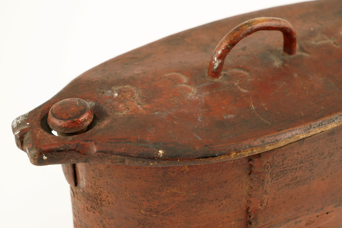 Nistelaup av rødmalt tre. Oval med svingbart lokk, festet i den ene enden med en trenagle. Hank og lås på lokket.